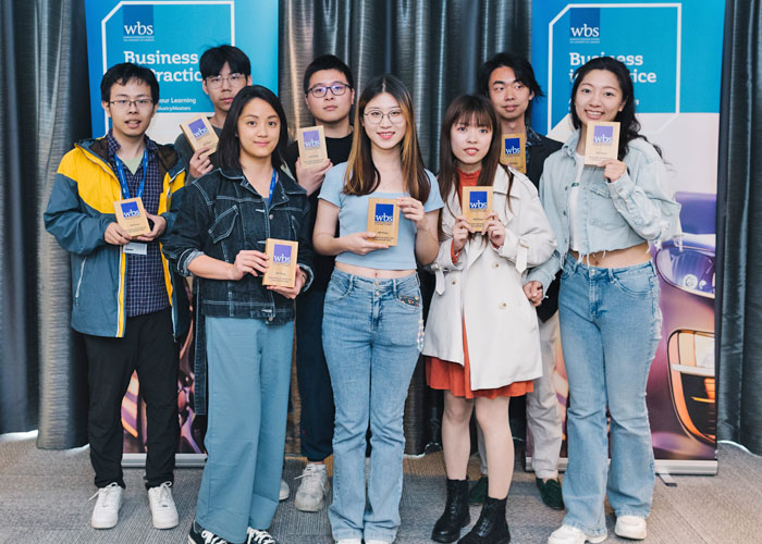 Eight WBS students holding their HR Prize at the Business in Practice 2024 Awards whilst smiling at the camera