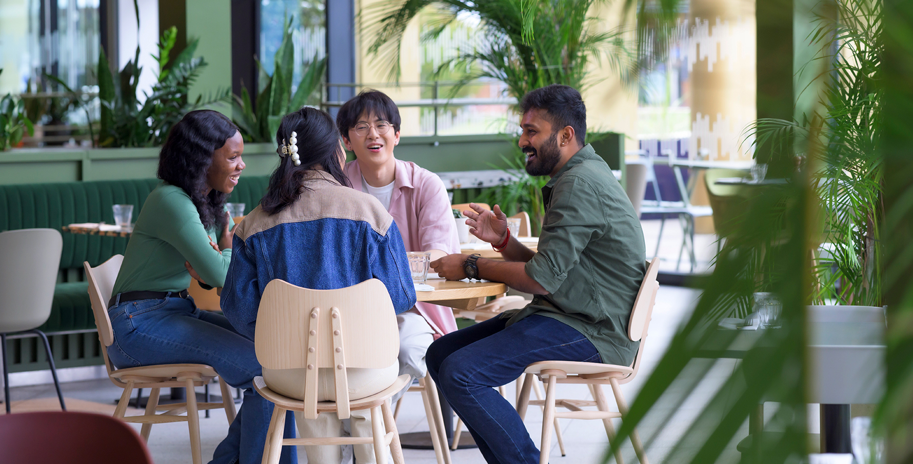 A group of students sat at a table in a cafe laughing and conversing