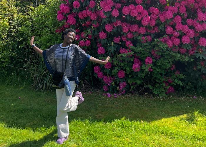 Bolu posing on the grass in front of a pink hydrangea bush in the sun