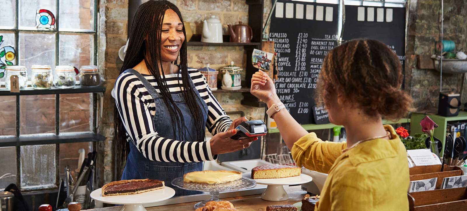 Young woman paying for goods with a smart watch in a coffee shop