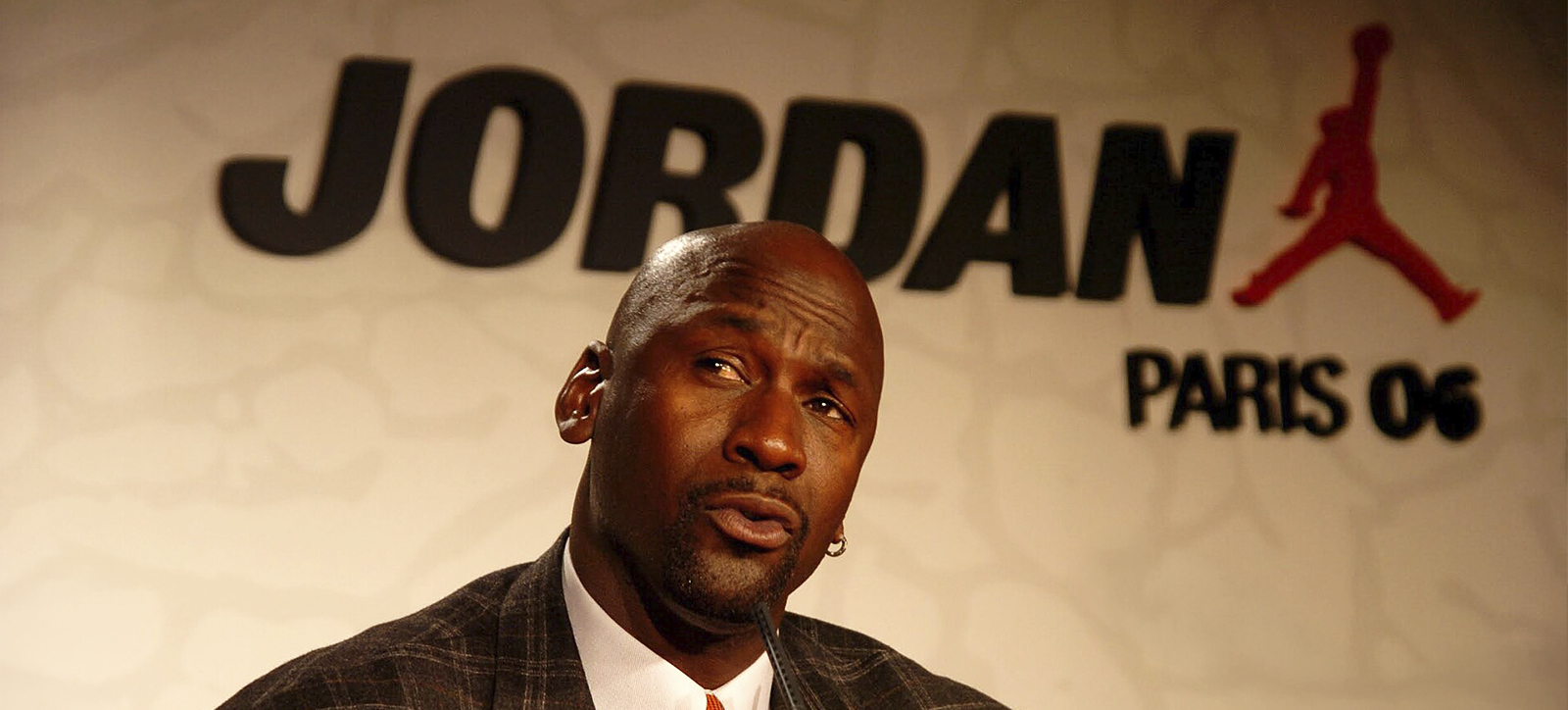 A photograph of Michael Jordan wearing as suit and answering questions at a press conference during a brand tour to Paris in 2006. The image was shared under creative commons by Nicolas Richoffer.