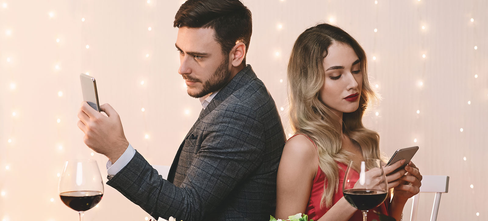 A couple on a date sit with their backs to each other, looking bored, as they each stare at their mobile phones. A couple on a date sit with their backs to each other, looking bored, as they each stare at their mobile phones.