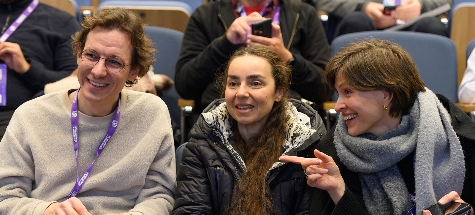 Three alumni laughing at the Warwick reunion in a lecture theatre
