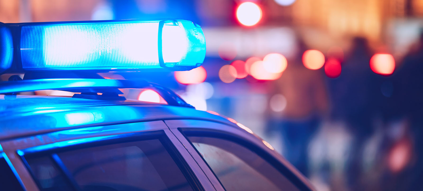 Flashing blue lights atop a police car during a stop and search operation in a UK city.