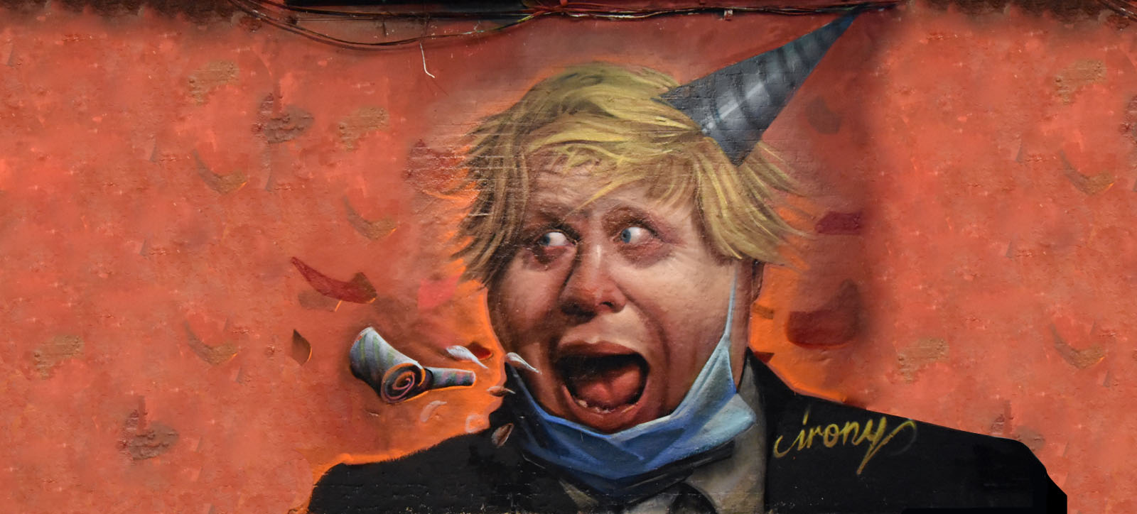 A mural of UK Prime Minister Boris Johnson wearing a party hat with his facemask pulled down, satirising the pandemic response and 'partygate' scandal