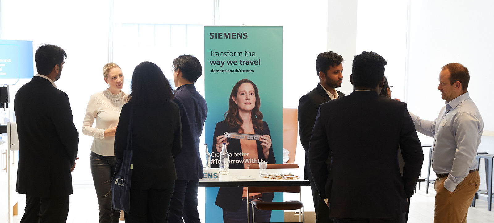 MBA students and graduates standing and talking around the Siemens stand MBA students and graduates standing and talking around the Siemens stand