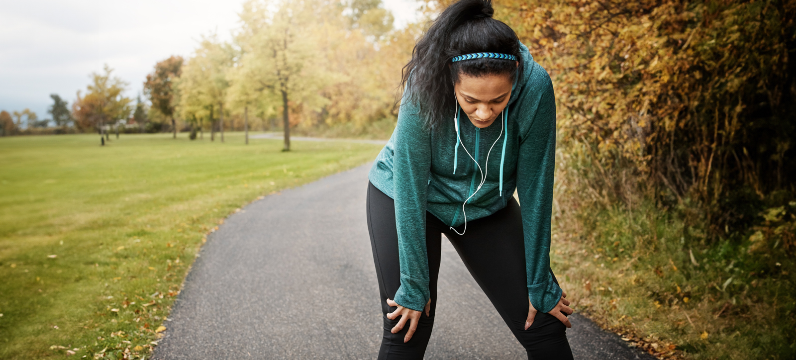 A tired runner stands with her hands on her knees, struggling to get her breath back. Nudging could help keep her exercising