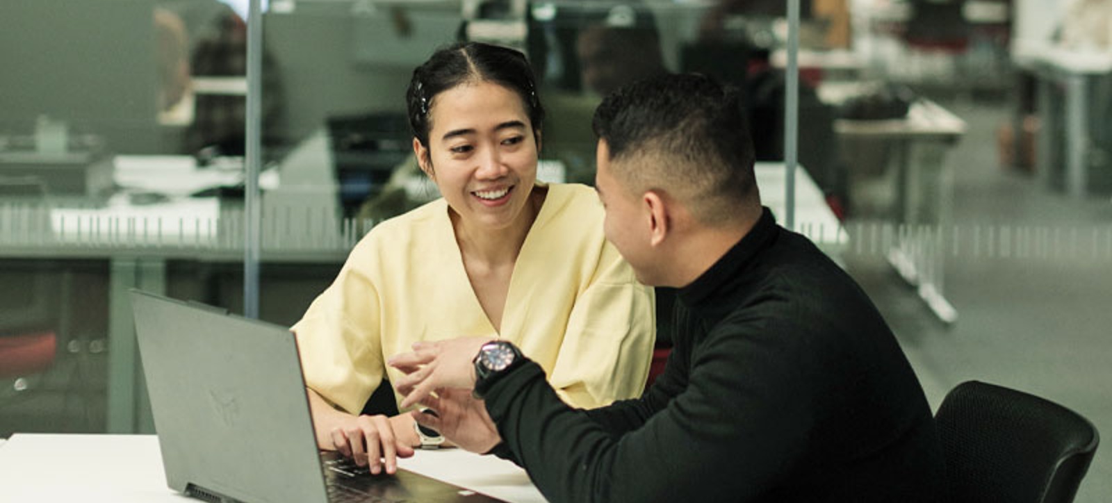 A girl and a boy Master's student discuss work over a laptop
