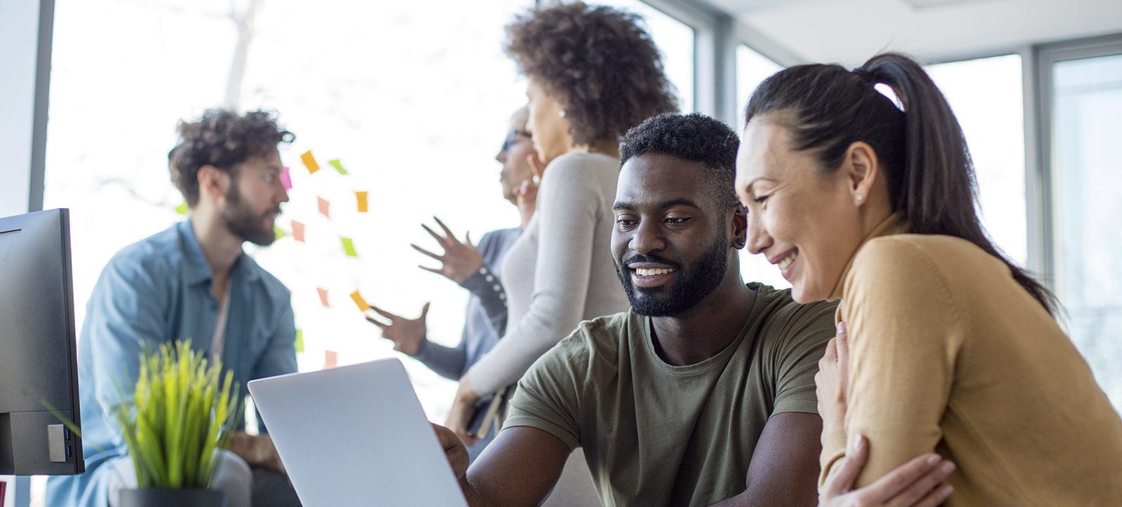 A diverse team busily working together over a laptop