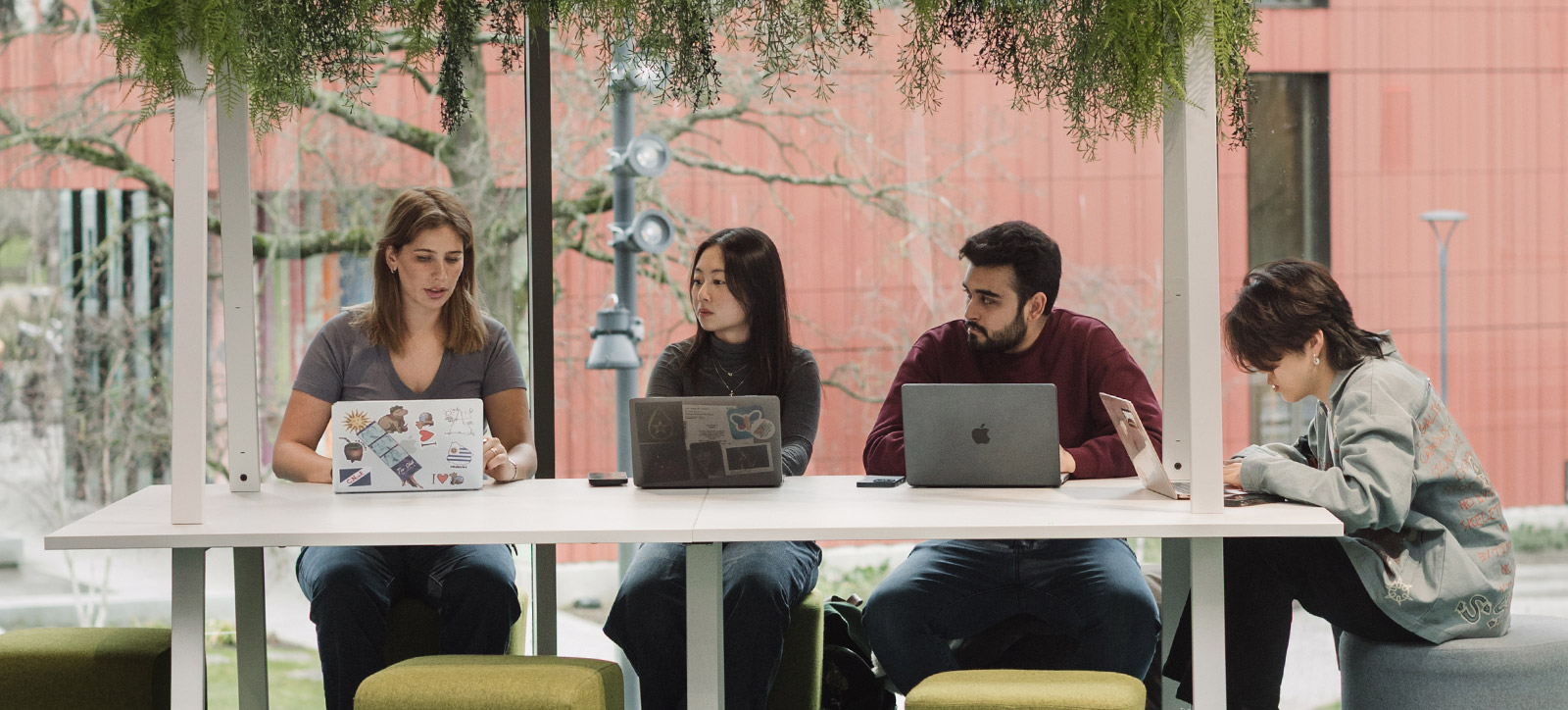 Four Master's students in discussion, two girls and two boys around a laptop at The Shard