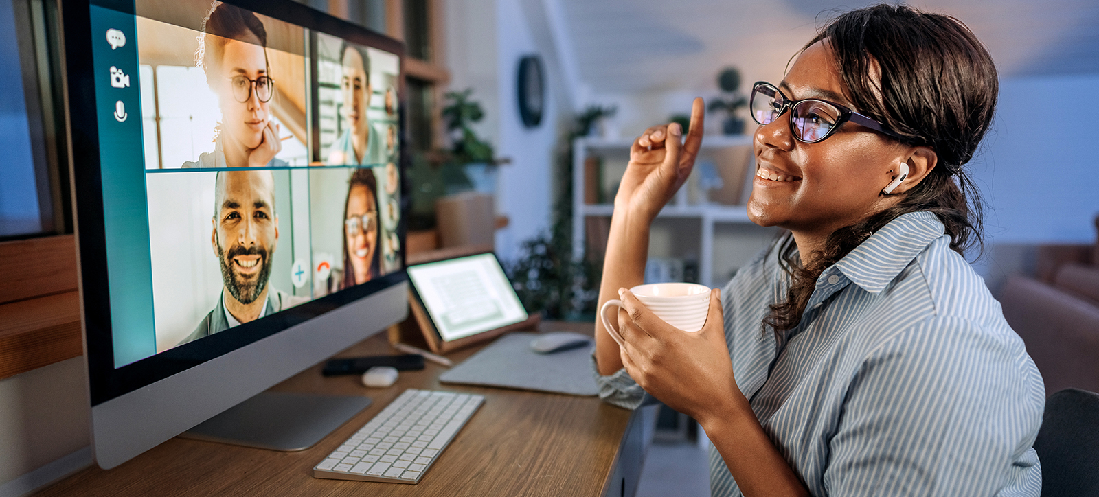 A young remote worker sat at a computer at home, meeting with colleagues through a video call. A young remote worker sat at a computer at home, meeting with colleagues through a video call.