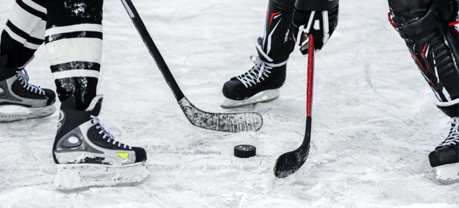 A close up of two ice hockey players facing off over a puck.