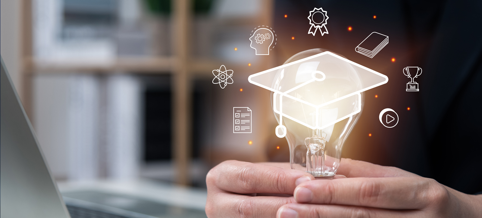 A hand holding a digitally generated lightbulb that is wearing a mortarboard academic cap and surrounded by idea icons A hand holding a digitally generated lightbulb that is wearing a mortarboard academic cap and surrounded by idea icons