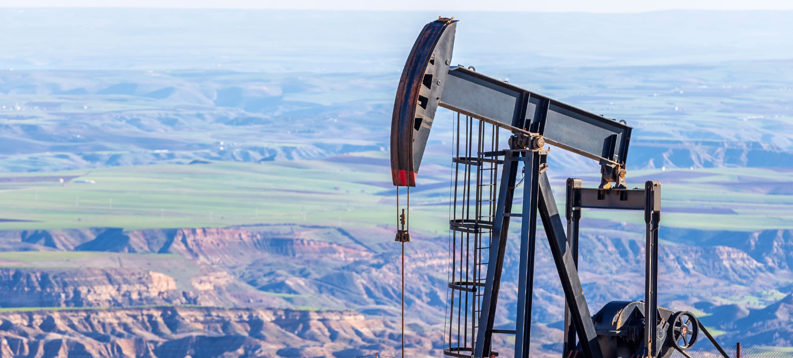 A pumpjack oil well in a baron landscape scarred by fossil fuel production. A pumpjack oil well in a baron landscape scarred by fossil fuel production.