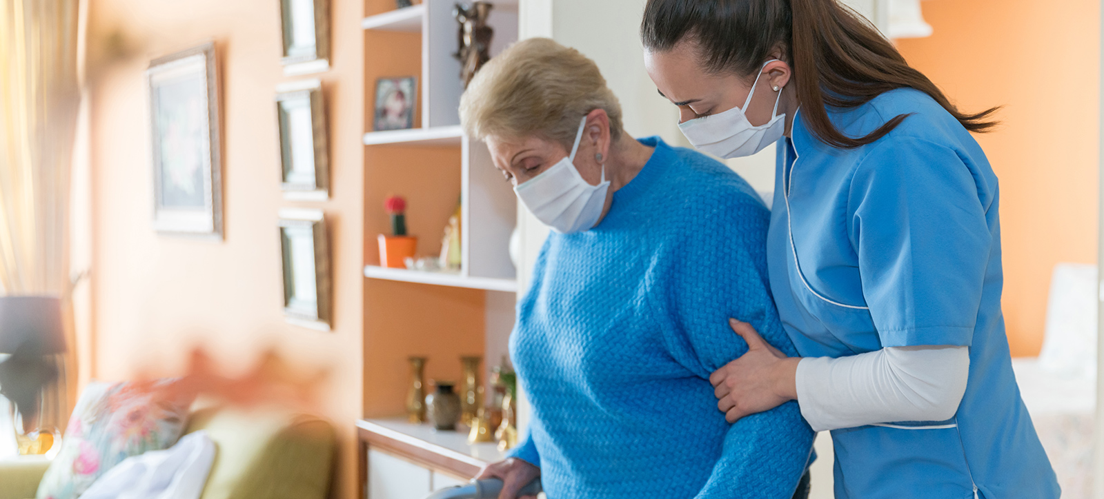 An elderly adult at a care home is helped by a care home worker An elderly adult at a care home is helped by a care home worker