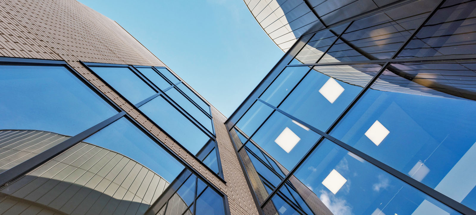 An upshot photo of a glass-walled and brick building under a blue sky. An upshot photo of a glass-walled and brick building under a blue sky.