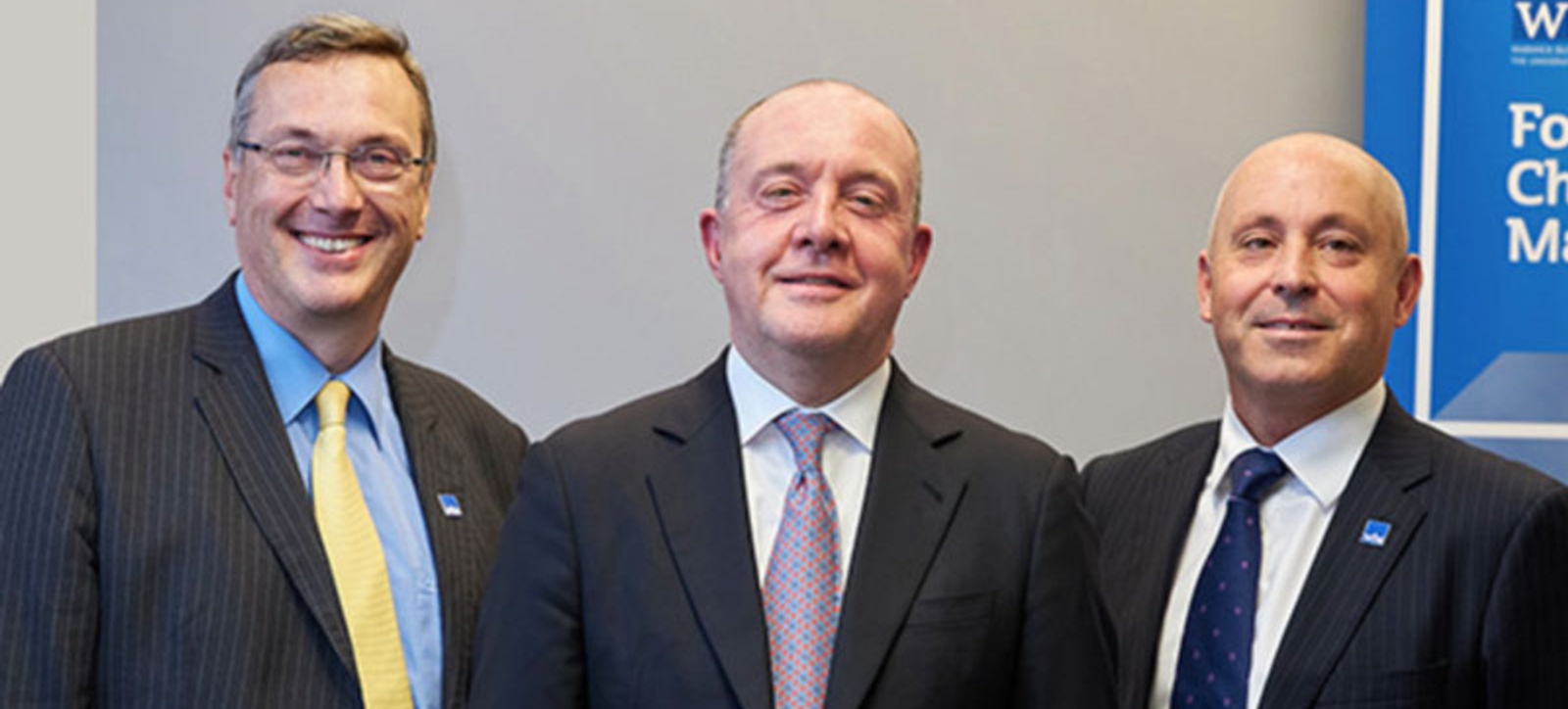 Clive Gillmore smiling at the camera alongside two other people who are dressed in suits. Clive Gillmore smiling at the camera alongside two other people who are dressed in suits.