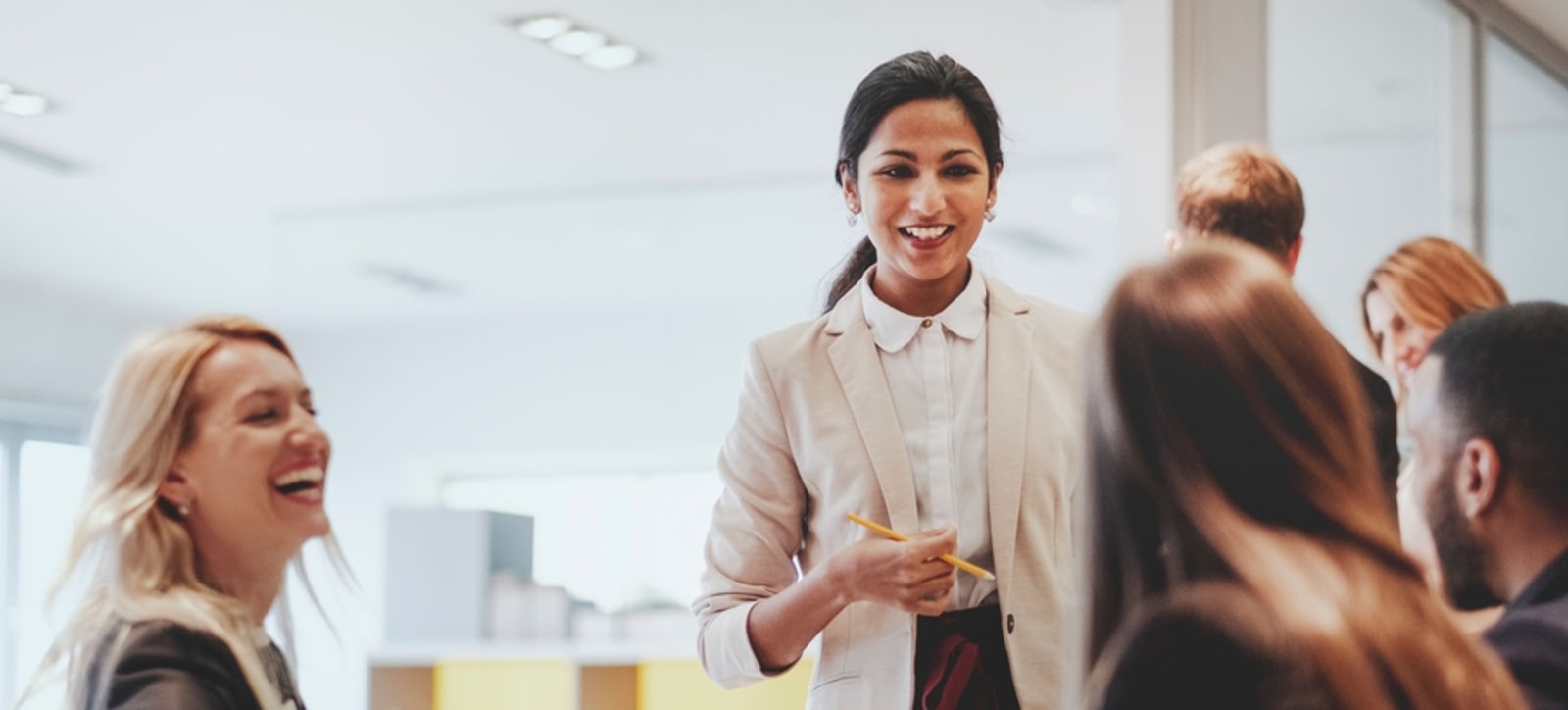Four people conversing a laughing with two other people blurred in the background.