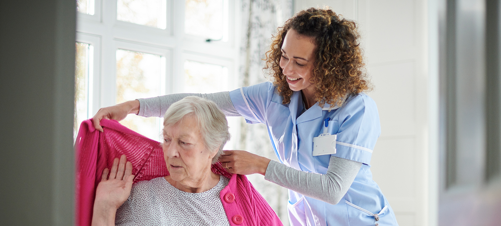 A care home worker helps a resident during the pandemic.