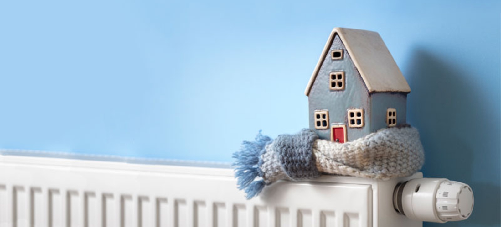 A model house wrapped in a scarf and sat on a radiator, symbolising the UK's need to reduce gas demand