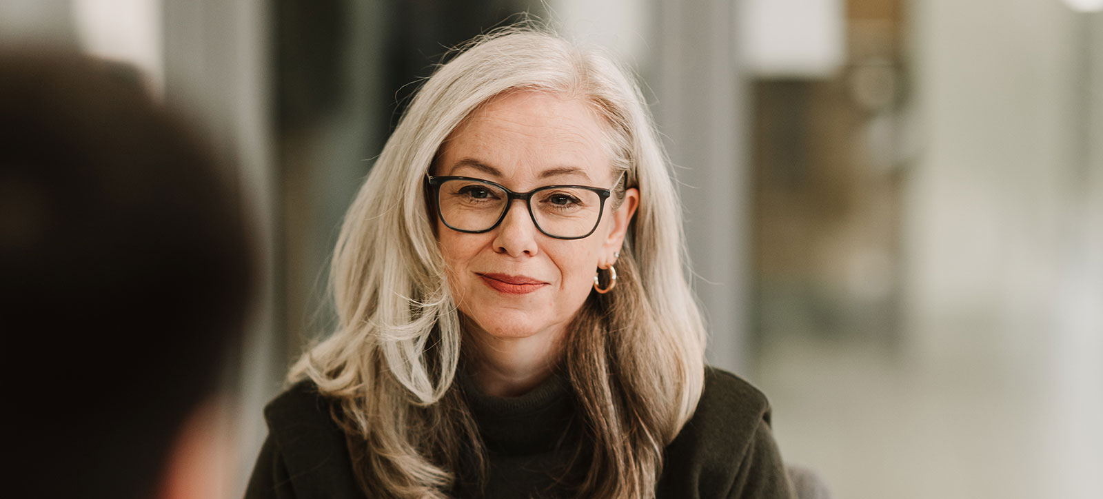 A grey haired woman with glasses studying for the Executive MBA