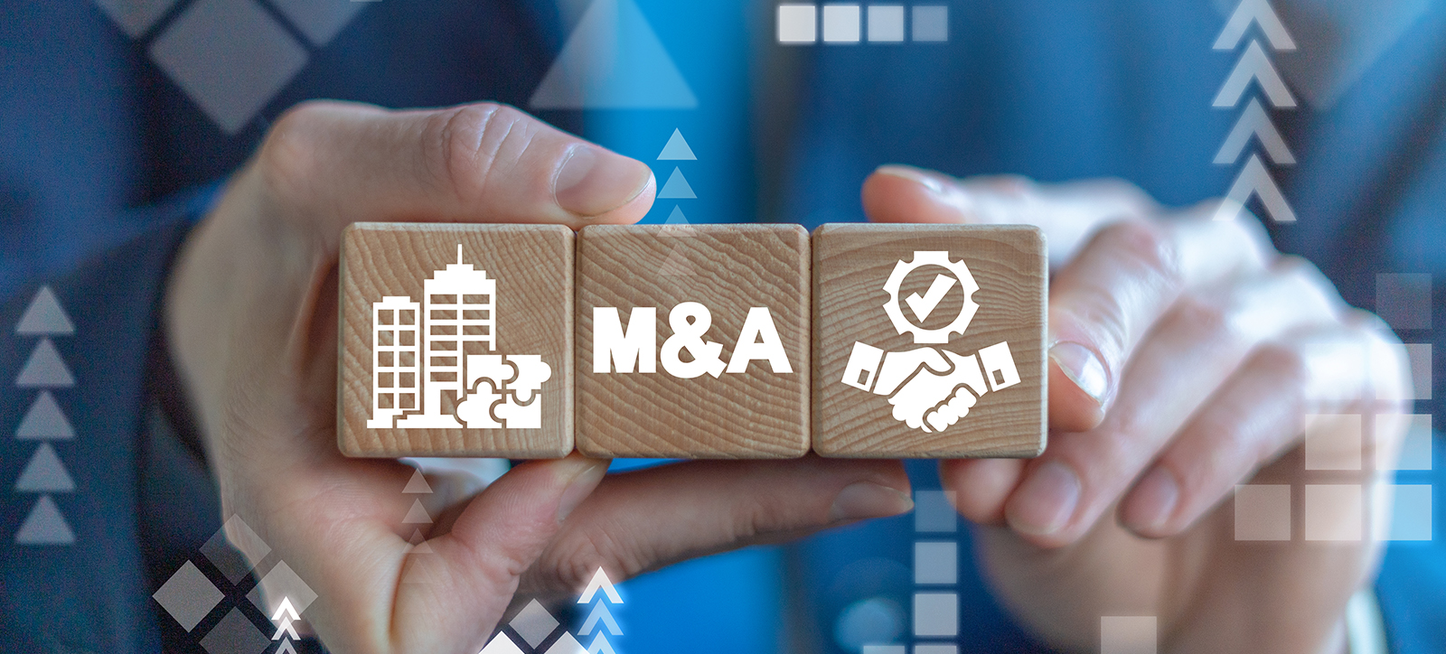 Two hands holding a series of wooden cubes showing the letters M&A Two hands holding a series of wooden cubes showing the letters M&A