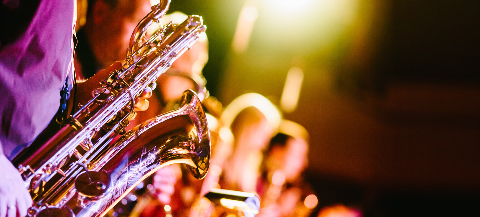 A saxophone player performing with a band with their bandmates in the background. A saxophone player performing with a band with their bandmates in the background.