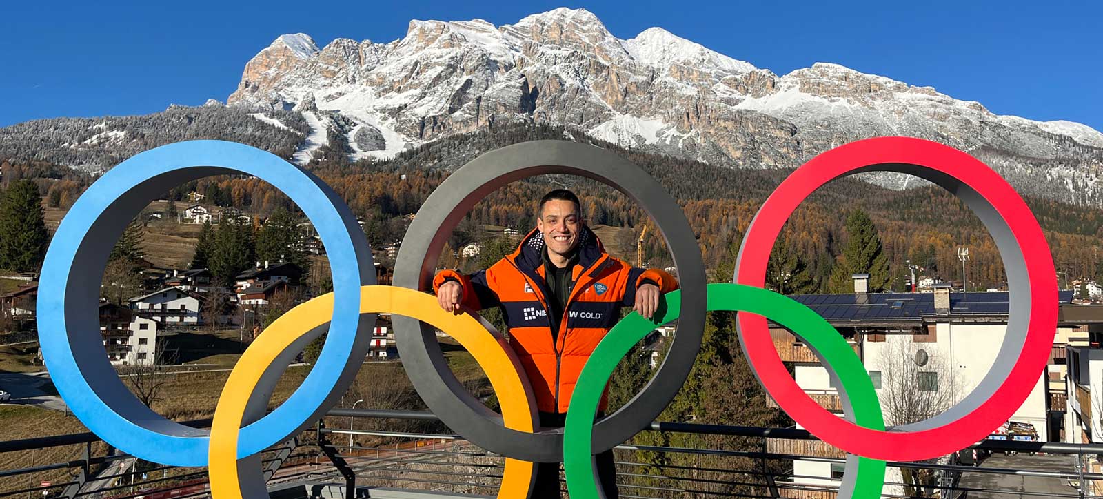 Paul Postema photographed with the iconic Olympic Rings in Cortina d'Ampezzo and the mountains behind him