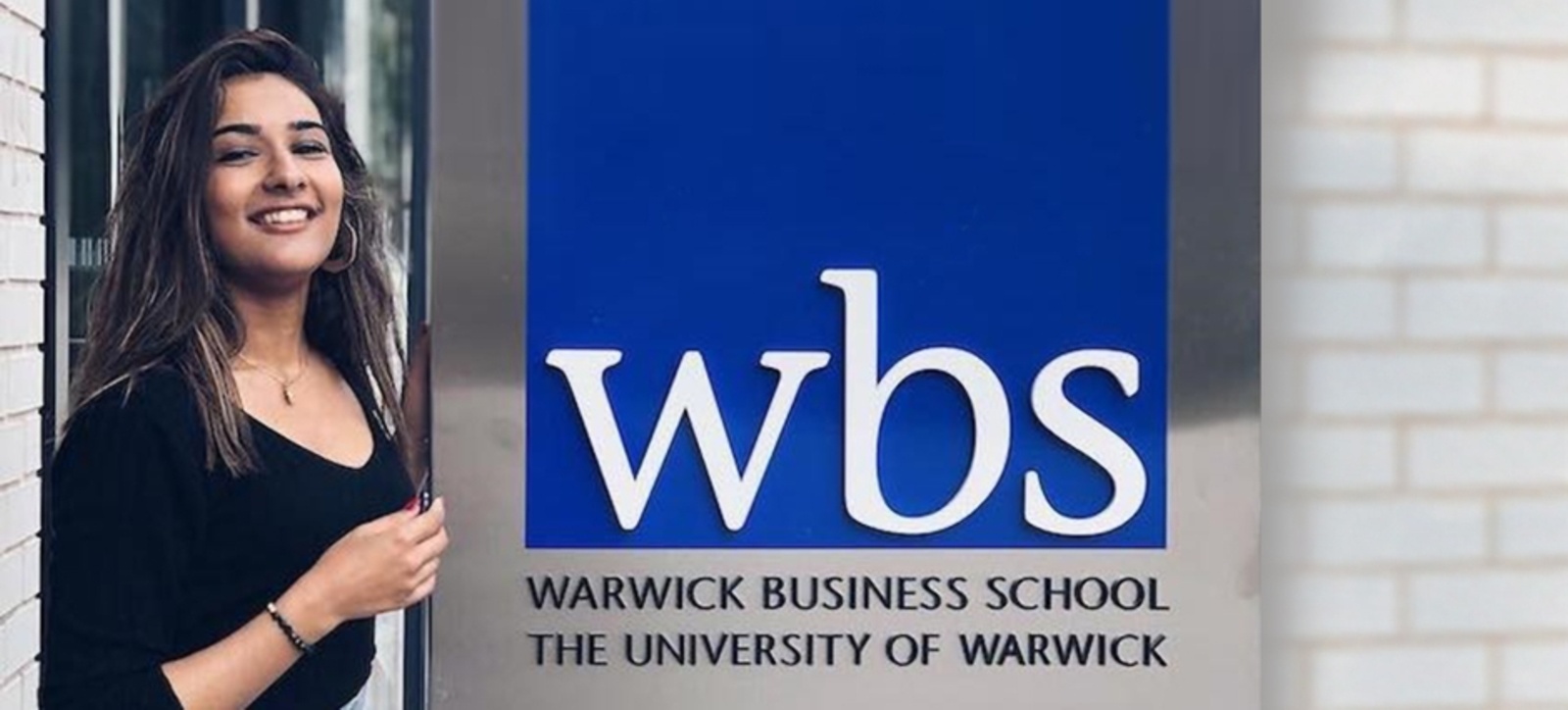 A happy student next to the WBS sign A happy student next to the WBS sign