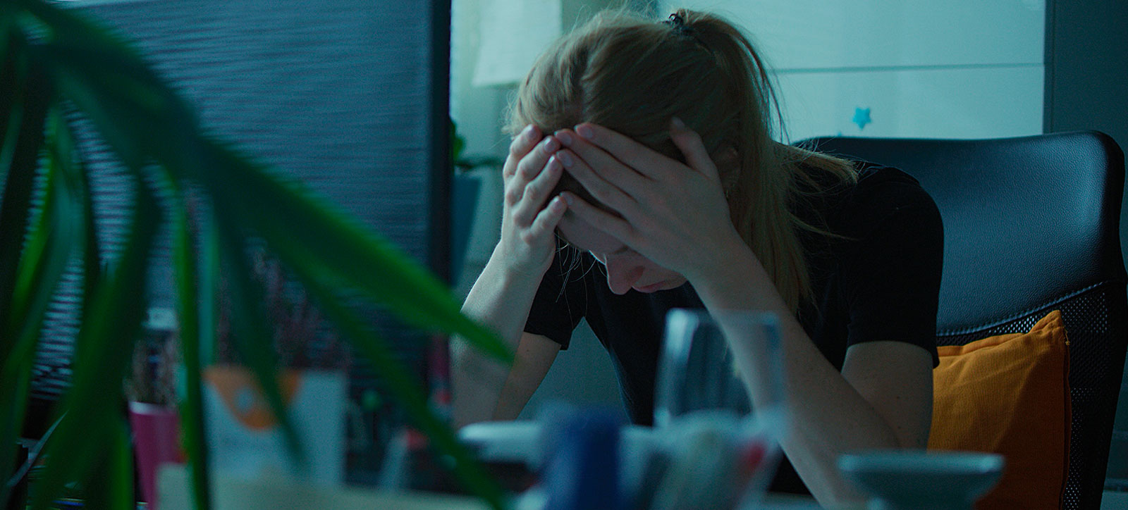 A woman with her head in her hands sat at her work desk A woman with her head in her hands sat at her work desk