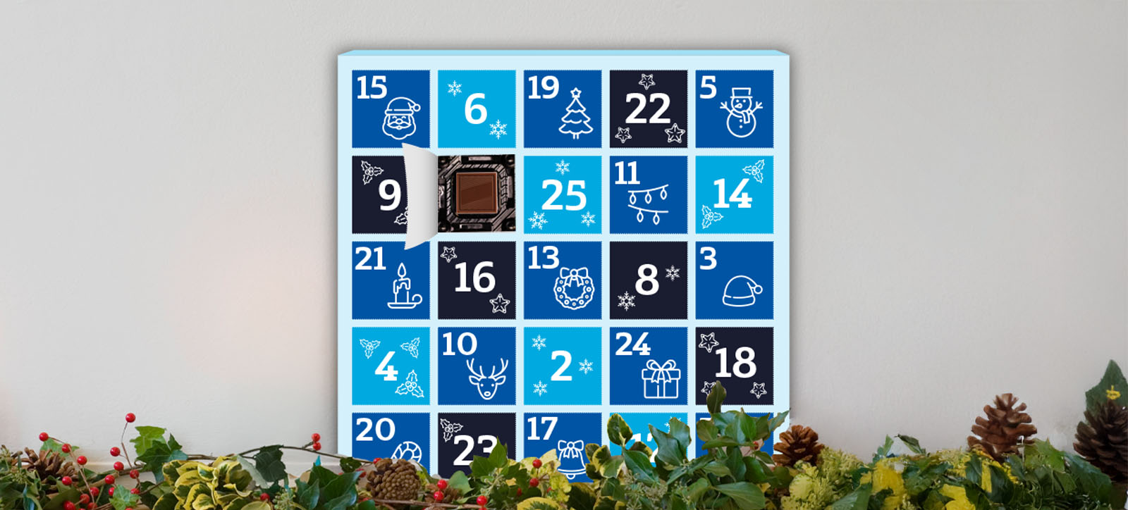 An advent calendar in Warwick Business School colours of light and dark blue. It sits on a mantelpiece with a decorative garland. One door of the advent calendar is open, revealing a chocolate treat inside.