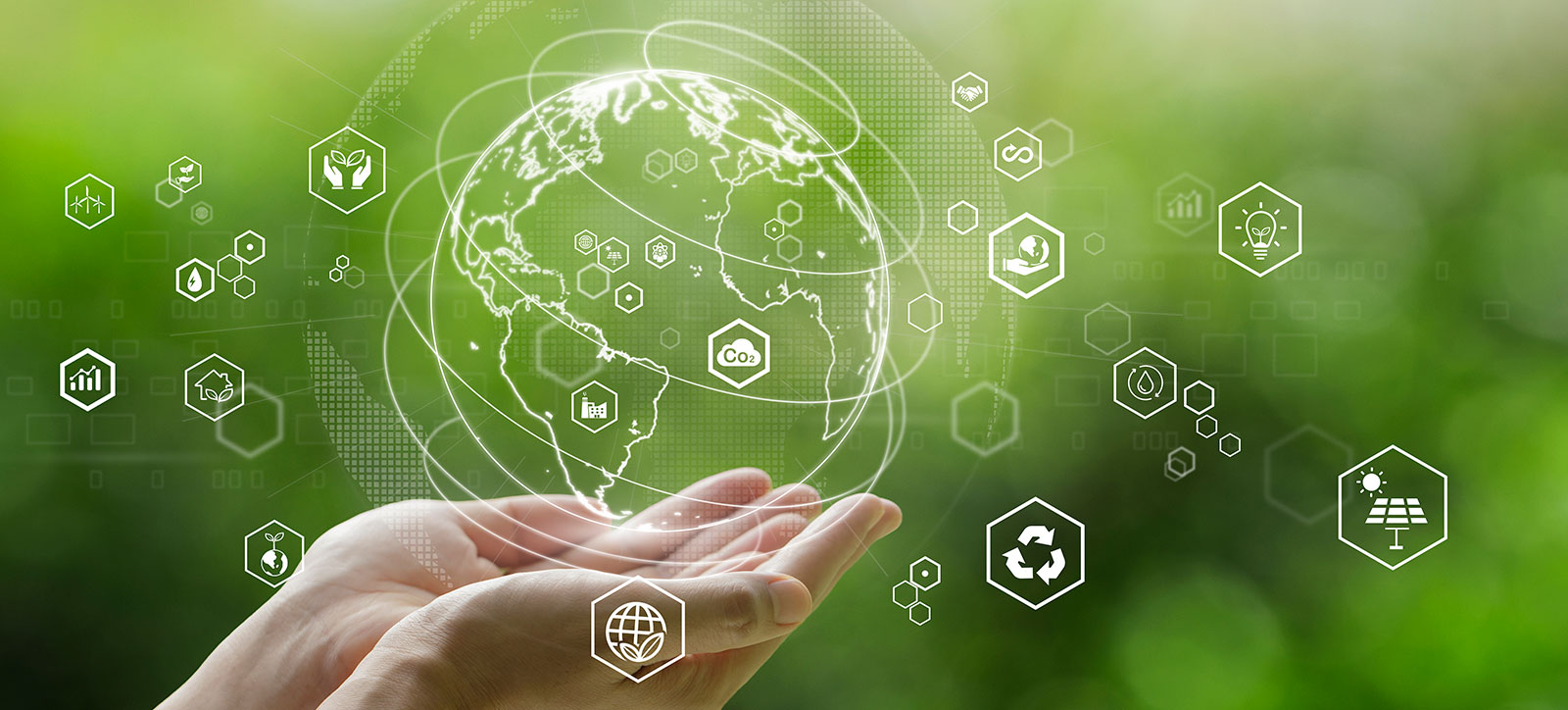 A pair of hands, held in a cupped position, cradle a digital image of planet earth. The planet is surrounded by icons representing different sustainability themes, such as recycling and solar power