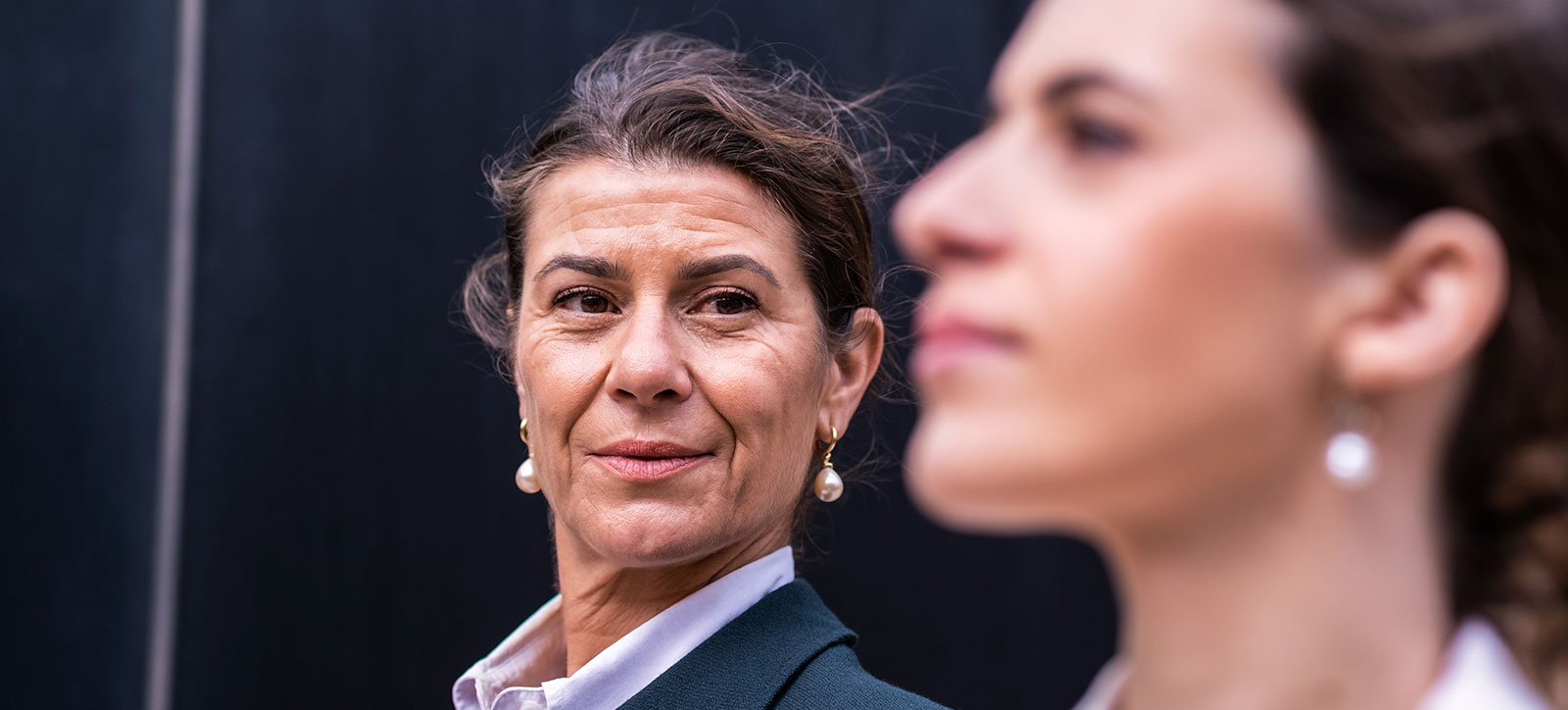 Two women walking with the older lady - a leader - staring at the younger one