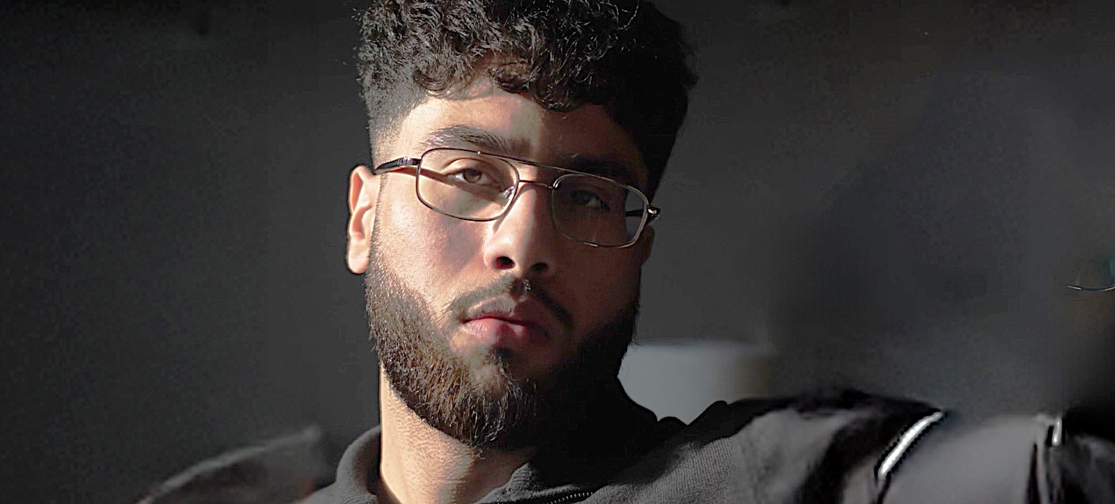 Ibrahim Malik in black and with a closely shaved beard
