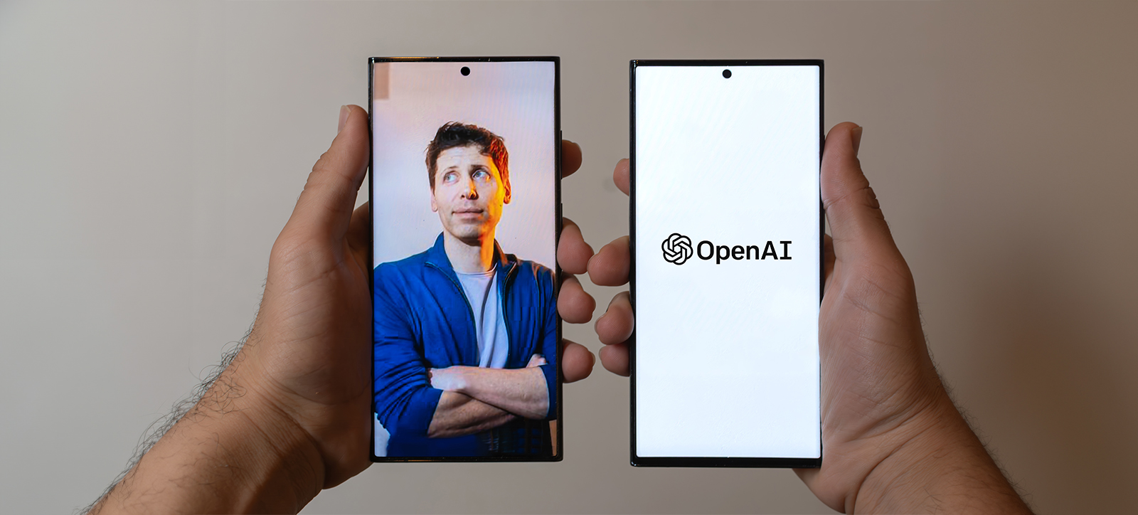 Two hands, each holding a mobile phone. One shows a photograph of ChatGPT creater Sam Altman stood with his sleeves rolled up and arms crossed, the other shows the OpenAI logo. Two hands, each holding a mobile phone. One shows a photograph of ChatGPT creater Sam Altman stood with his sleeves rolled up and arms crossed, the other shows the OpenAI logo.