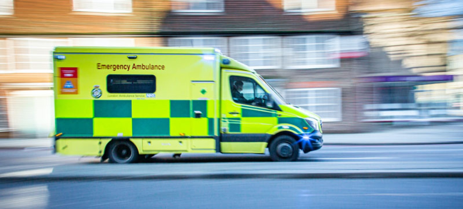 An emergency ambulance driving fast on a residential street. An emergency ambulance driving fast on a residential street.