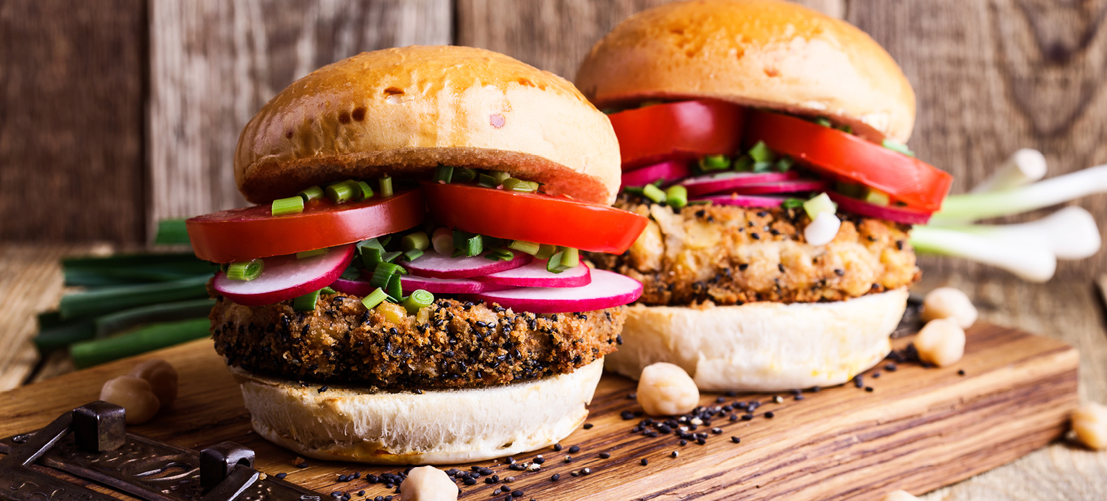 Two meat-free burgers sit on a wooden chopping board, ready to be served in a fast food restaurant