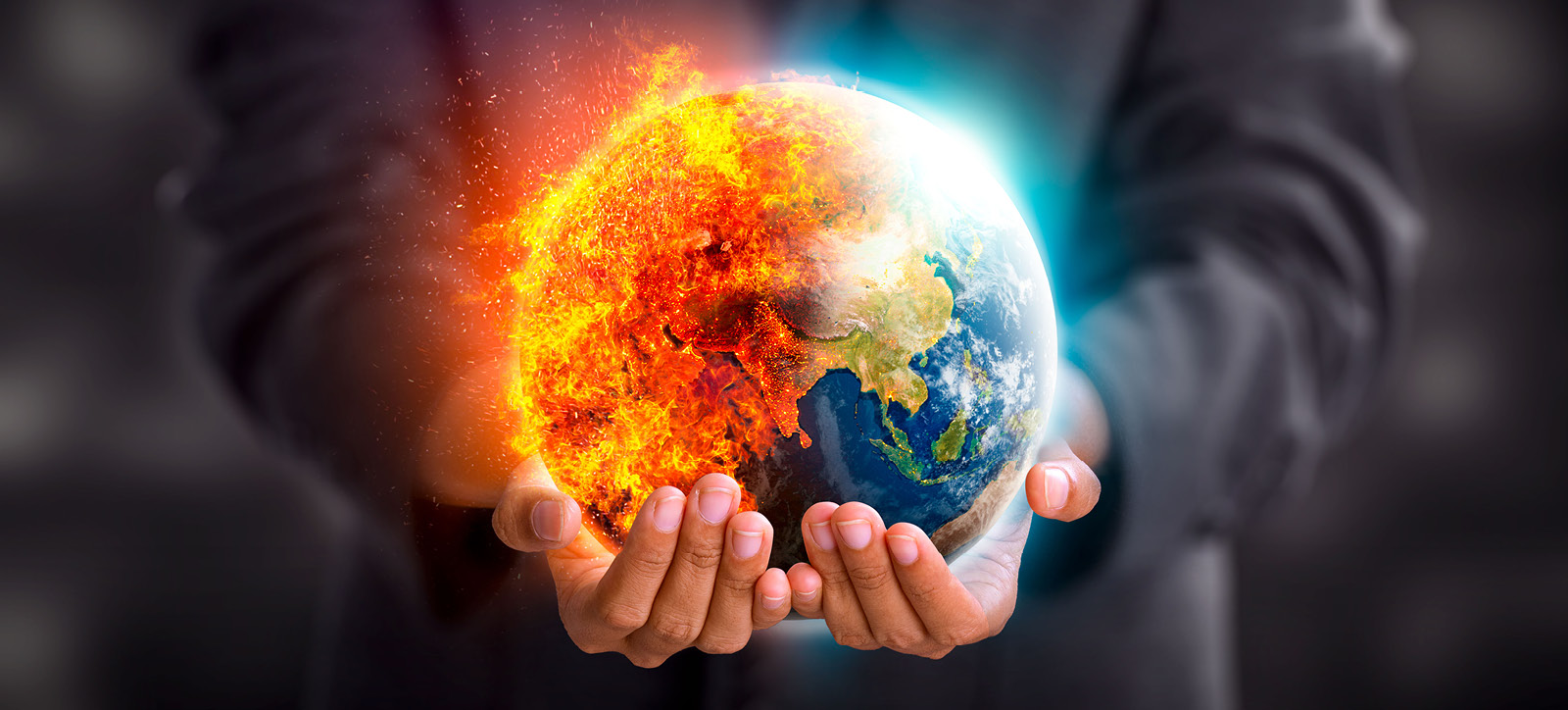 A businessman in a suit cradles a burning image of planet Earth in his hands