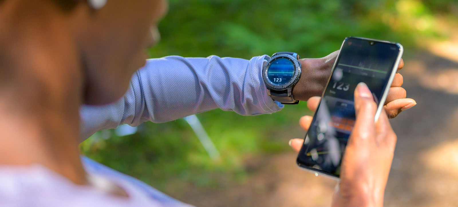 A woman takes a break from exercising to check her performance on her wearable tracking device.